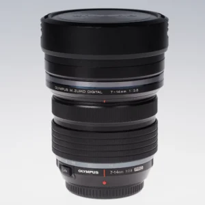 Olympus M.Zuiko 7-14mm f2.8 Pro -objektiivi pystyasennossa, vastavalosuoja ja etusuojus paikallaan