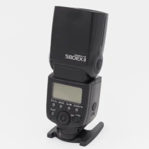 Canon Speedlite 580EX II -salama sivukuvassa jalustallaan, musta runko ja LCD-näyttö näkyvissä